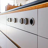 Detail runder BORA Bedienknöpfe an der Kücheninsel, weiße Front unter dunkler Arbeitsplatte