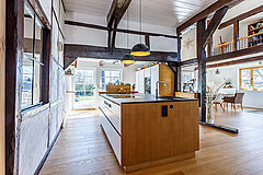 Längsansicht des Küchenblocks mit dunkler Arbeitsplatte, offene Wohnküche im Fachwerkhaus