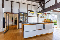 Küchenblock im Fachwerkhaus mit geöffnetem Auszug, griffloses Design in Weiß und Holz