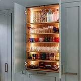 Landhausküche in Salbeigrün, Hamburg Altona | maßgefertigt von der Möbeltischlerei woodendesign – innen beleuchter Innenschrank für Gläser, Vasen & Karaffen