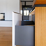 Detail eines grifflosen Auszugs mit seitlicher Griffmulde am Küchenblock, Weiß und Holz