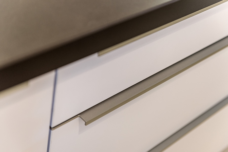 Große Küchenschubladen mit Griffleiste aus Edelstahl und weißen Fronten
