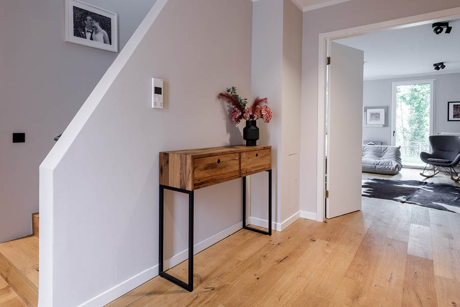 Konsolenschrank aus Altholz mit zwei Schubladen und schwarzem Metallgestell im hellen Flur; Blickachse ins Wohnzimmer, leichte Anmutung. Aktuelles – Trends – News im November 2025 | Möbeltischlerei woodendesign | Tischlerei Möbeltischler Möbelmanufaktur Hamburg