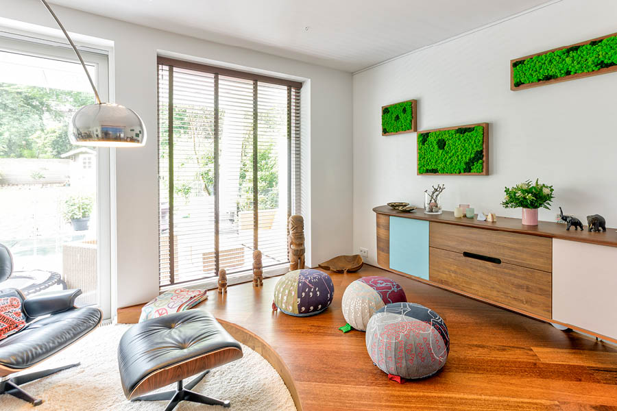 Wohnzimmer mit langem Lowboard/Sideboard; Holzfronten mit Farbakzenten, Moos-Wandbilder, bodentiefes Fenster, aufgeräumtes Gesamtbild. Aktuelles – Trends – News im November 2025 | Möbeltischlerei woodendesign | Tischlerei Möbeltischler Möbelmanufaktur Hamburg