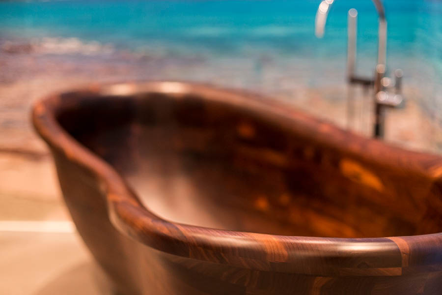 Nahaufnahme freistehende Holzbadewanne in dunkler Maserung; weiche Radien, geölte Oberfläche, stimmungsvolles Licht. Holz im Badezimmer | Aktuelles – Trends – News im Dezember 2025 | Möbeltischlerei Tischlerei Möbeltischler Möbelmanufaktur Hamburg