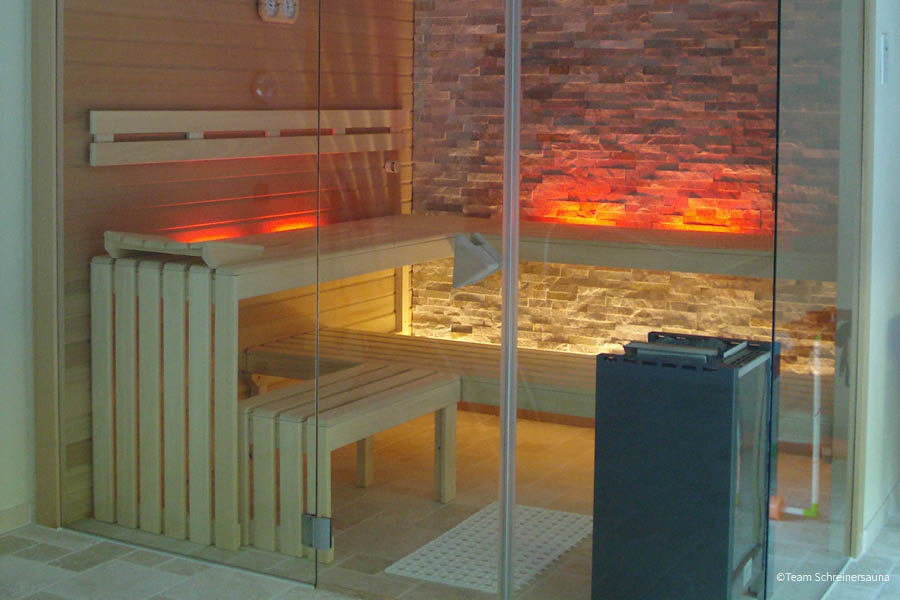 Klassische Sauna mit Holzbänken, Saunaofen und beleuchteter Natursteinwand | Sauna Wärmekabine Infrarot | Aktuelles – Trends – News im Juli 2026 | Möbeltischlerei Tischlerei Möbeltischler Möbelmanufaktur Hamburg