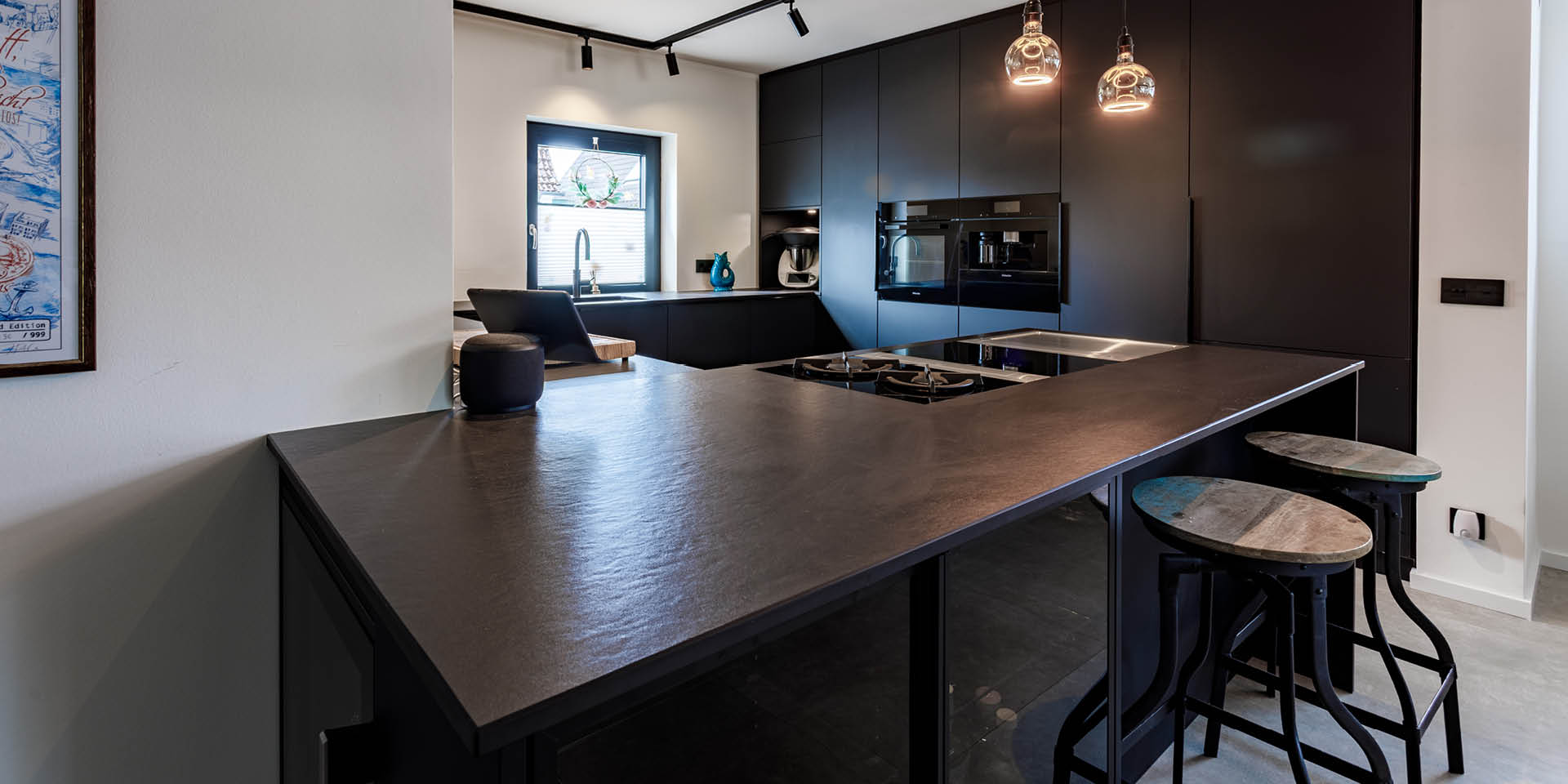 Mattschwarze Designküche in Hamburg-Mitte in G-Form mit offener Gestaltung, Kochblock und Hochschrankwand im Industrial Style.